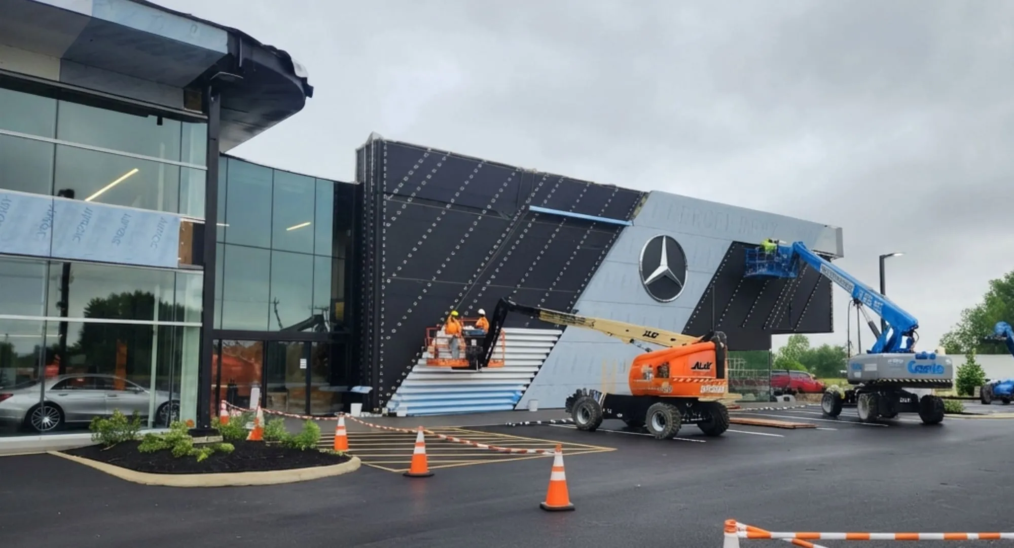 Lifts and crew installing the illuminated lamella façade at a Mercedes-Benz dealership