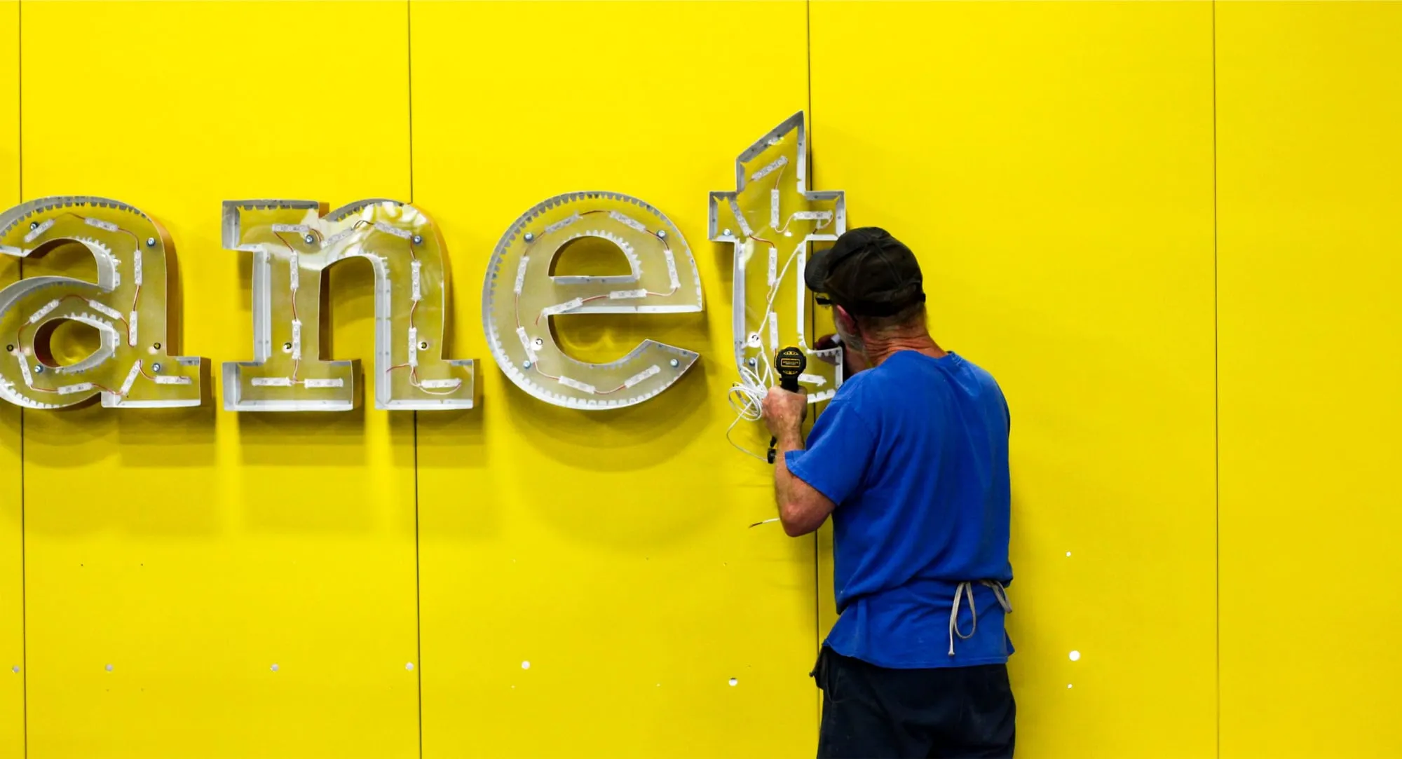Installer fitting illuminated channel letters to a storefront