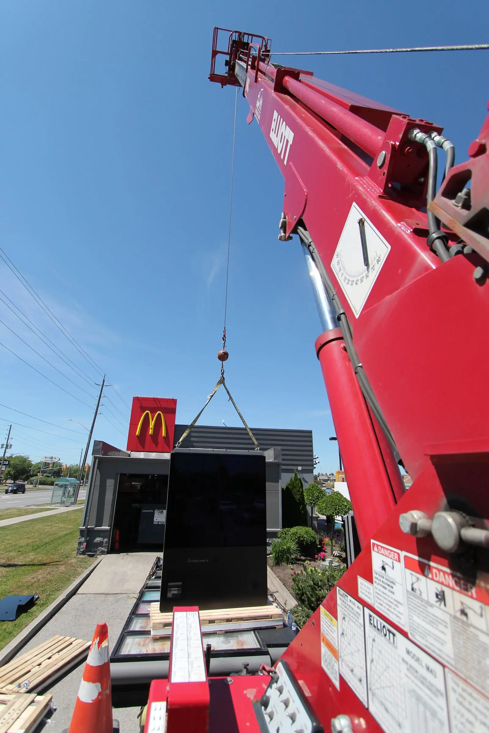 Digital menu board suspended from the crane as it is lowered into position