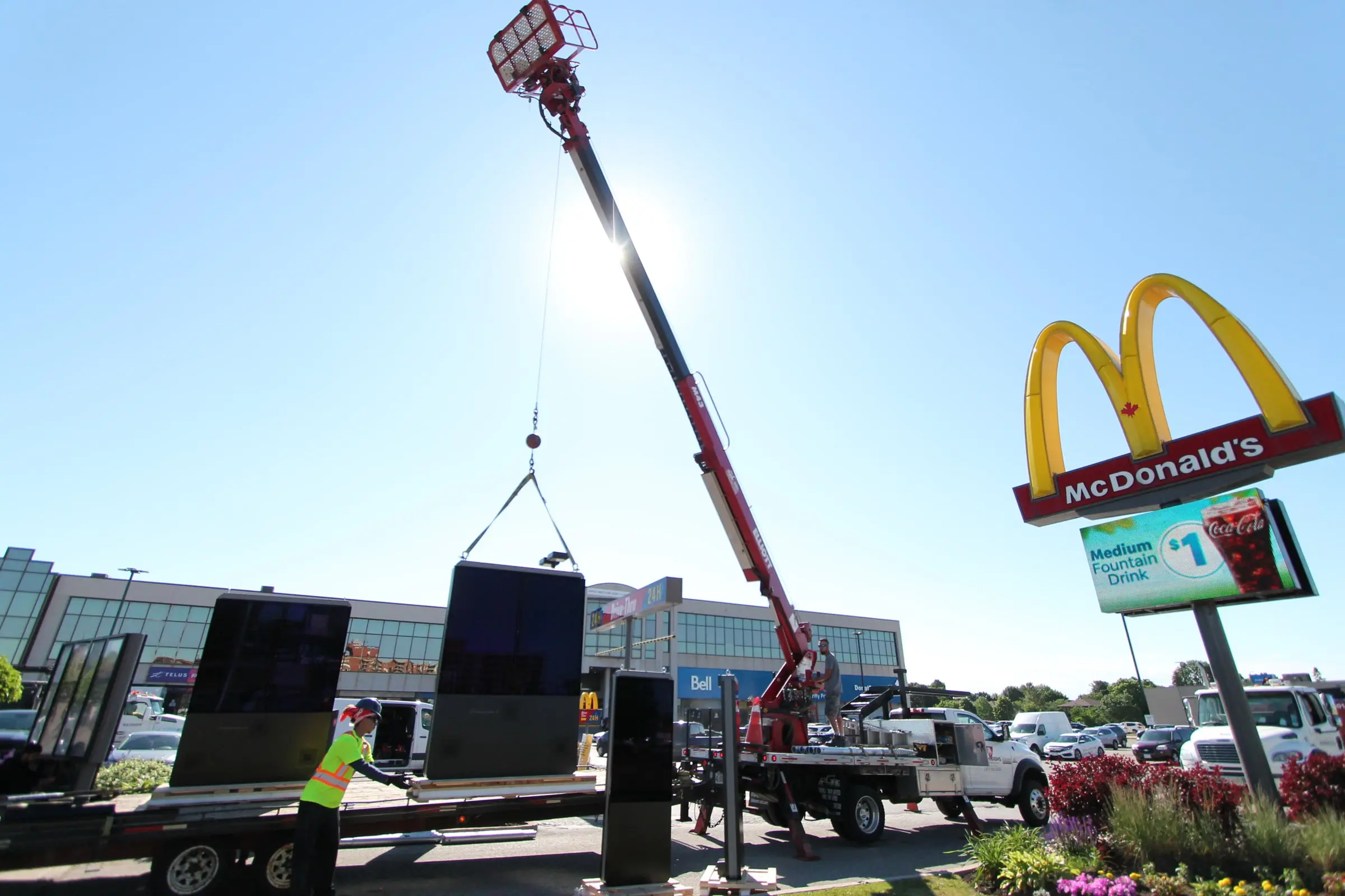 Crane lifting a digital menu board from the trailer beside the McDonald’s pylon sign