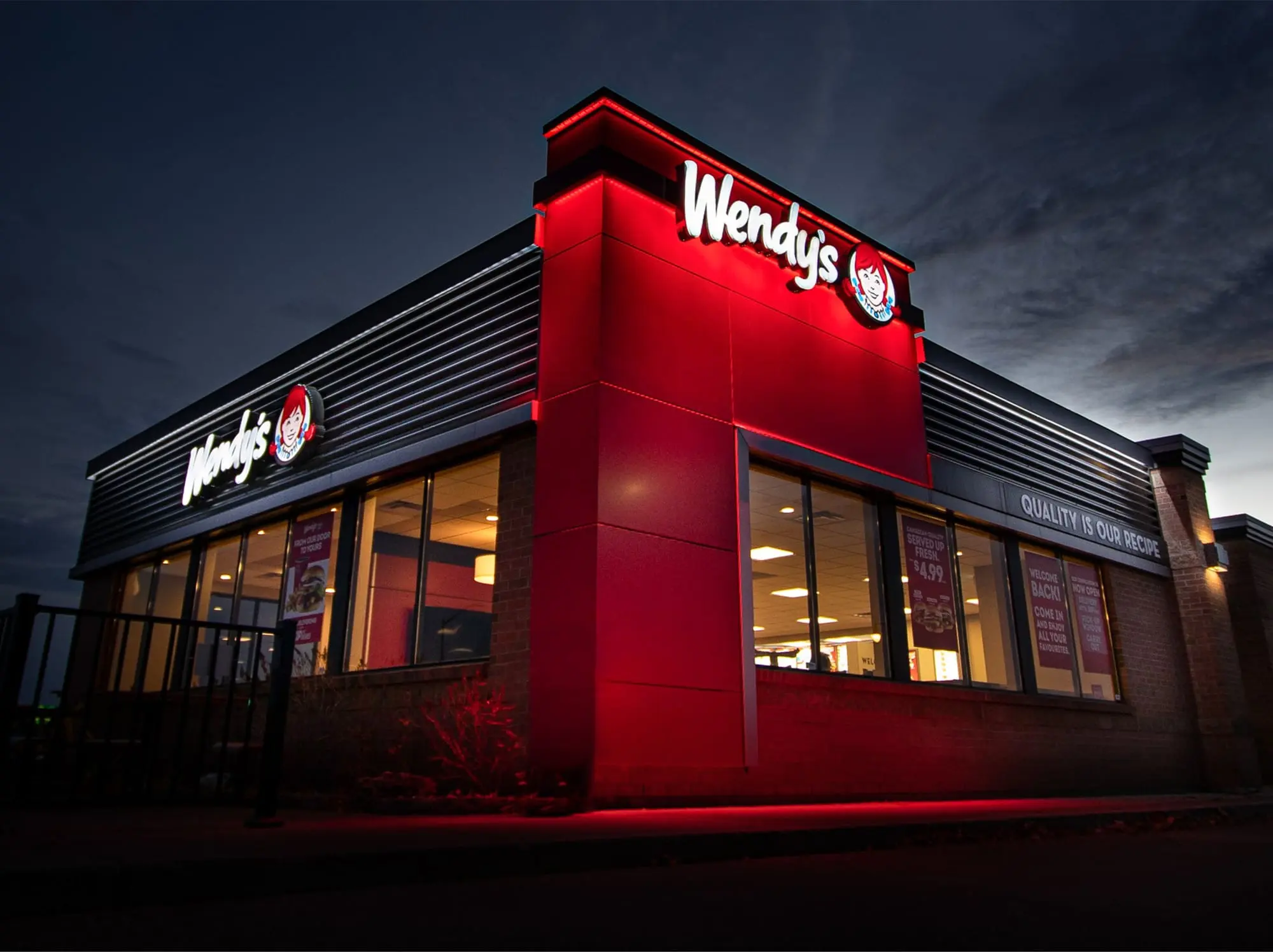 Illuminated Wendy’s canopy and channel letters glowing red at dusk