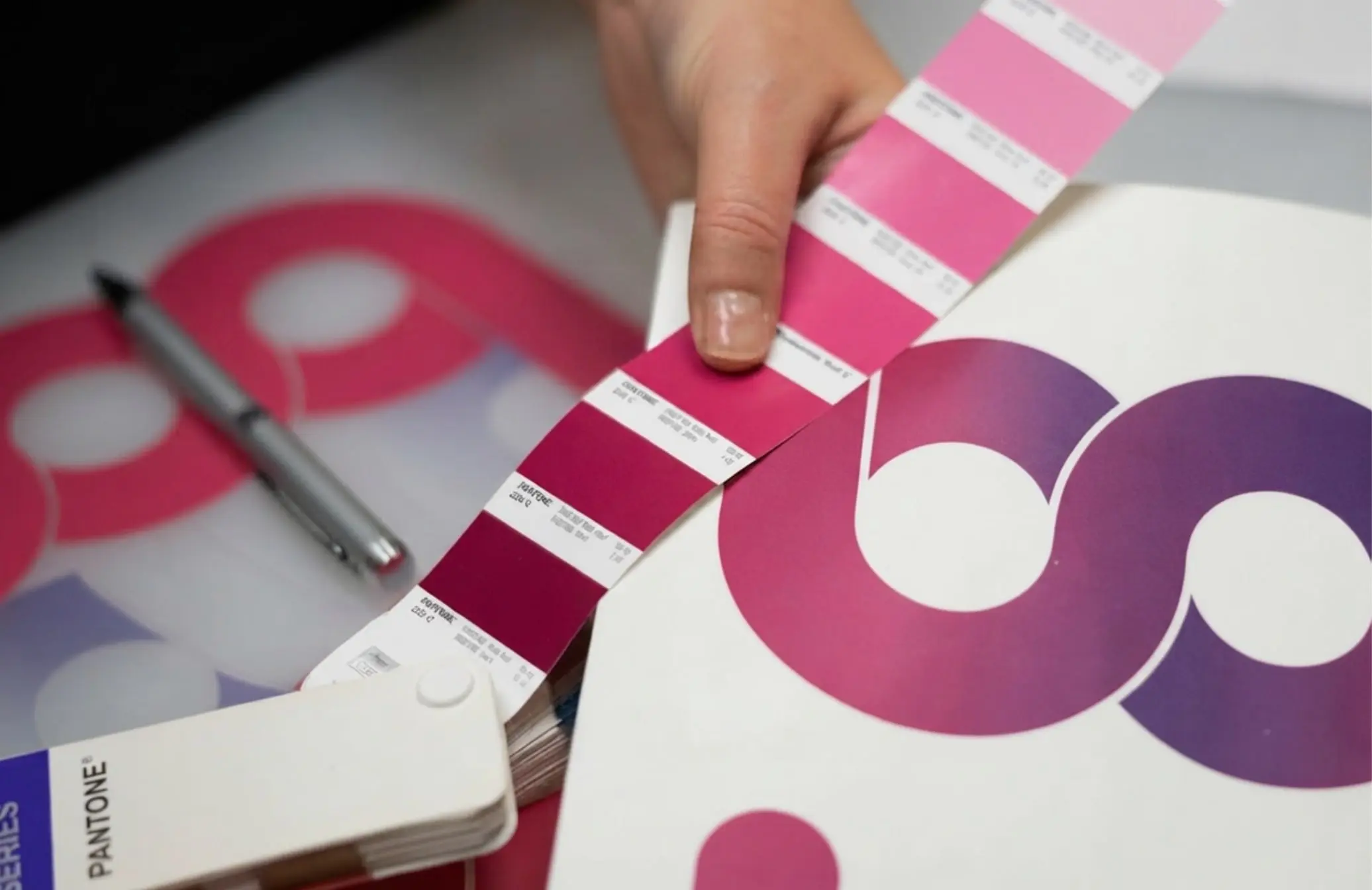 Designer matching a Pantone swatch fan against printed brand artwork