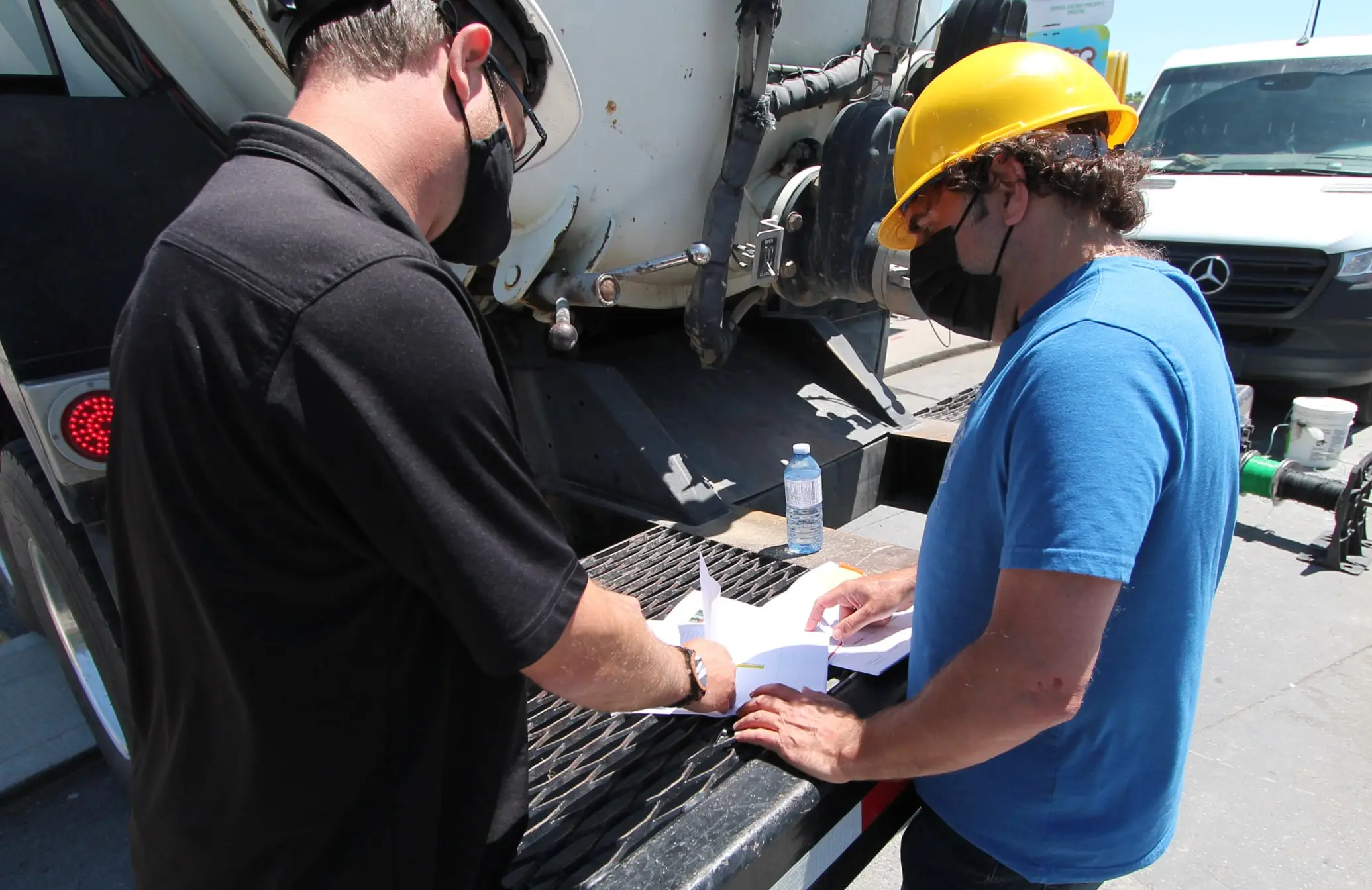 Project managers reviewing job paperwork at the back of a service vehicle on site