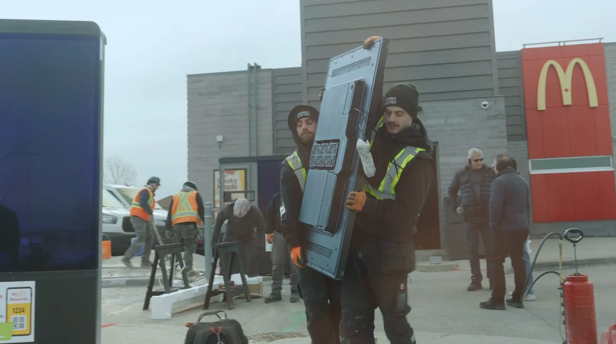 Pride Visual Solutions installation crew carrying a digital menu board on site
